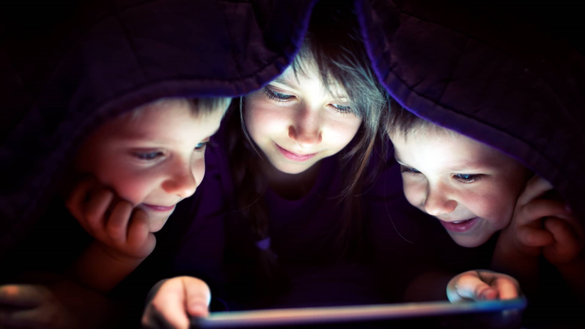 Børn ser ipad under dyne. Deres forældre tager sikkerhed på nettet alvorligt. De har fået 7 gode råd til at være sikker på nettet og sikker shopping på nettet.