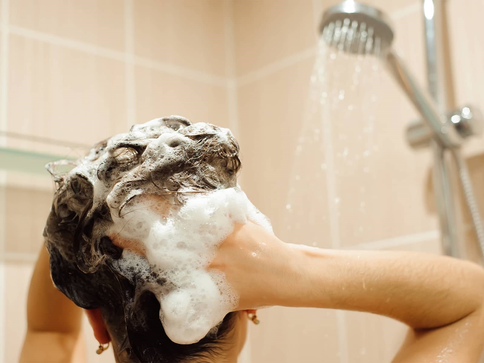 Kvinde vasker hår i badet